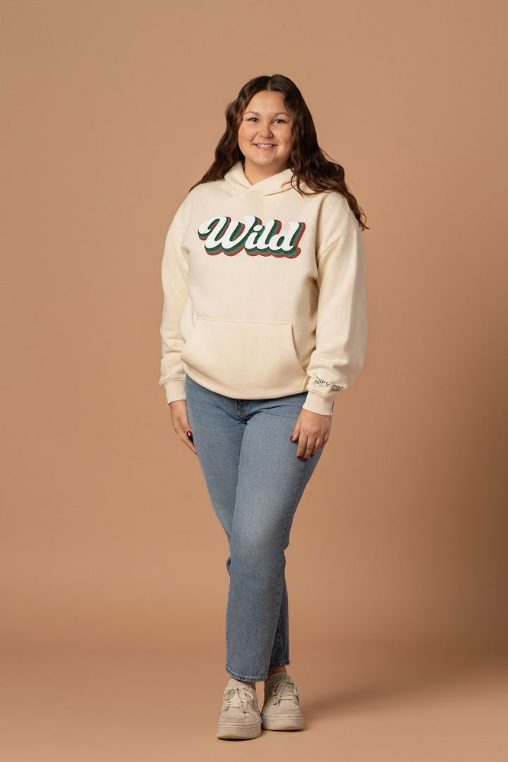 woman standing in a womens wild hockey ivory hoodie sweatshirt that is a retro style