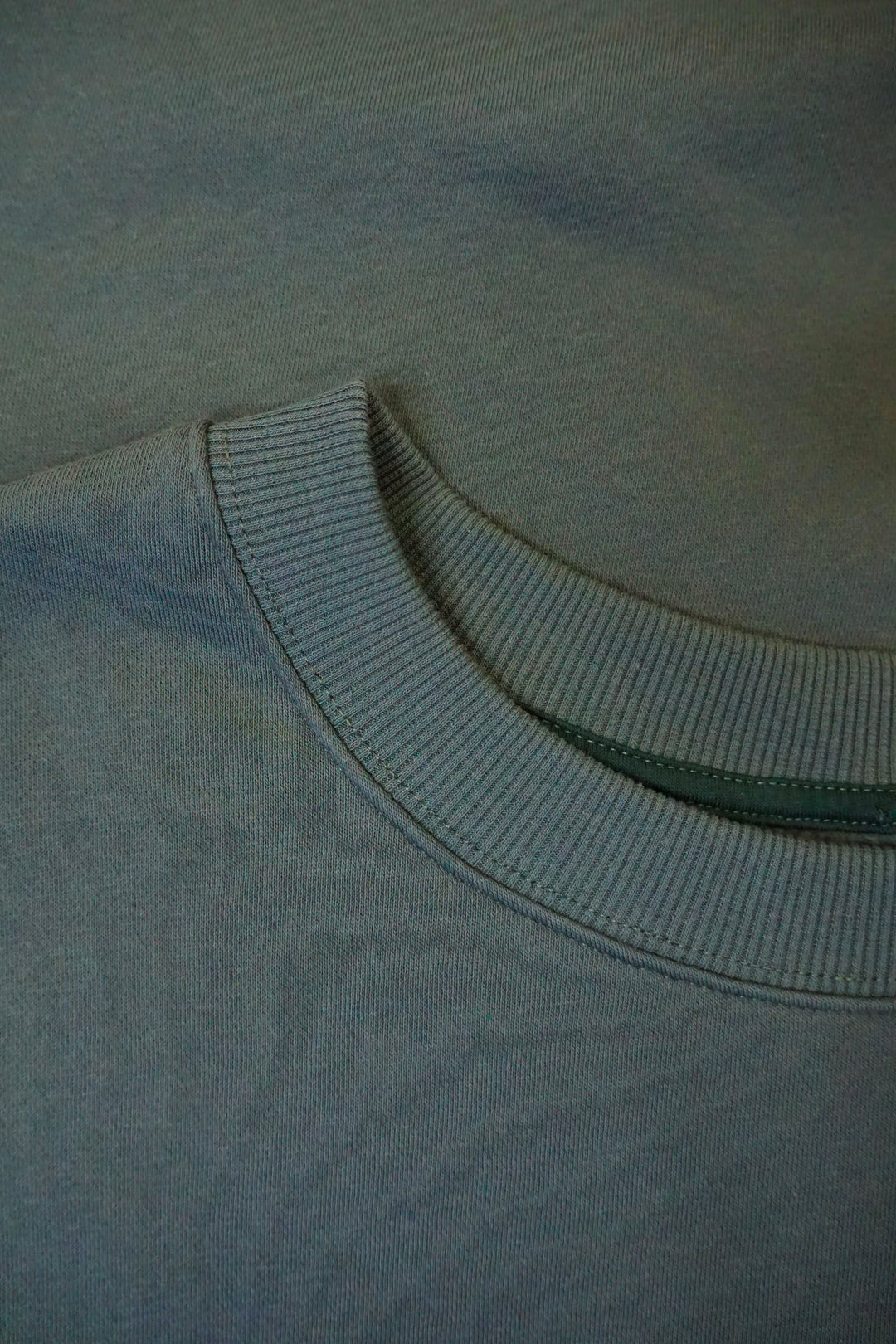 A close up photo of a dark green collar on a crew neck.