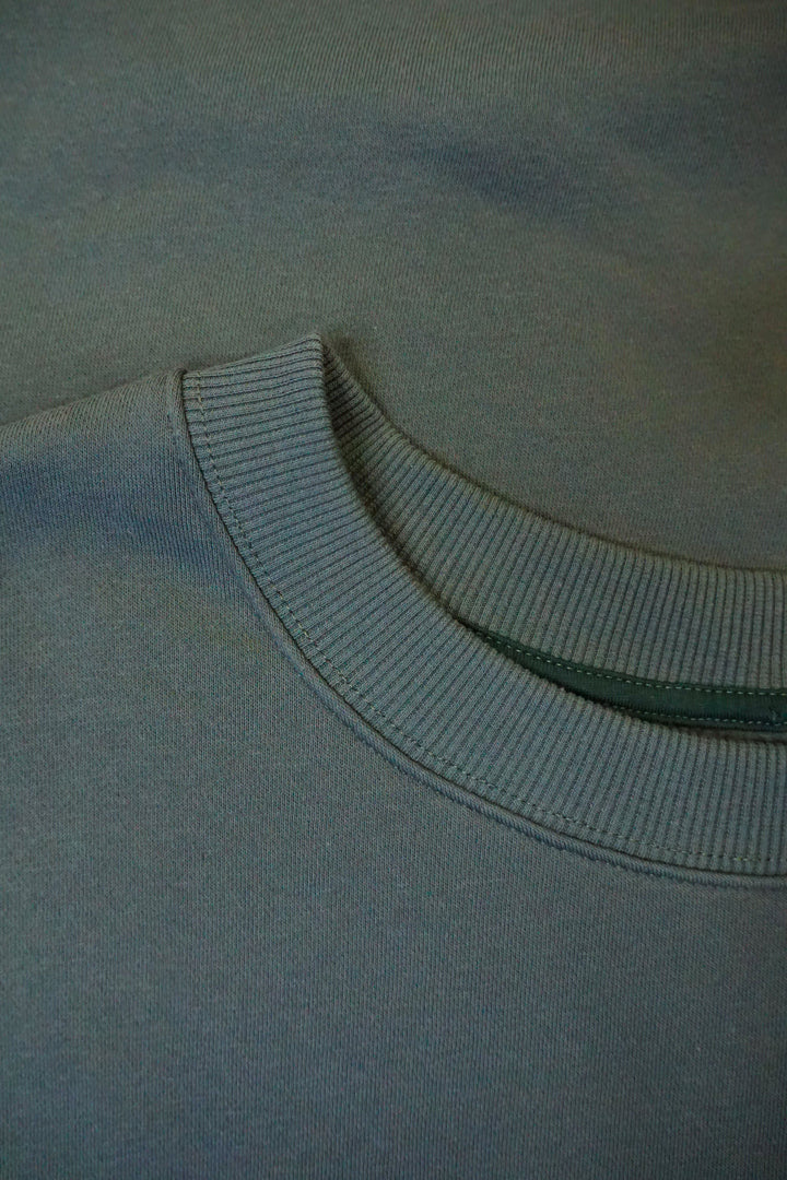 A close up photo of a dark green collar on a crew neck.