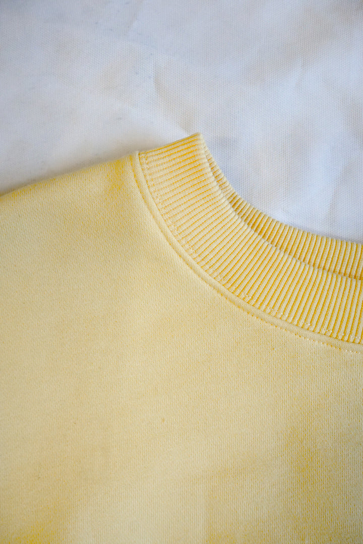 Close-up of a yellow crew neck sweatshirt neck line 
