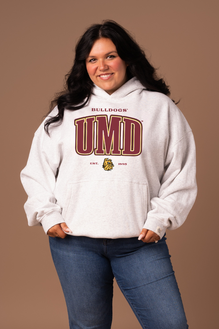 Woman wearing a grey hoodie with 'Bulldogs' and 'UMD' text in maroon with a gold outline