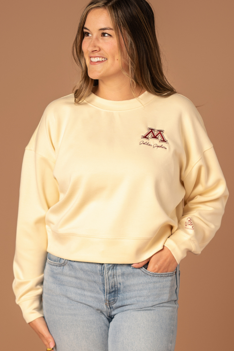 close up image of a girl wearing a black supersoft crewneck with a M logo and Golden Gophers embroidered in maroon on the left side pocket of the crew
