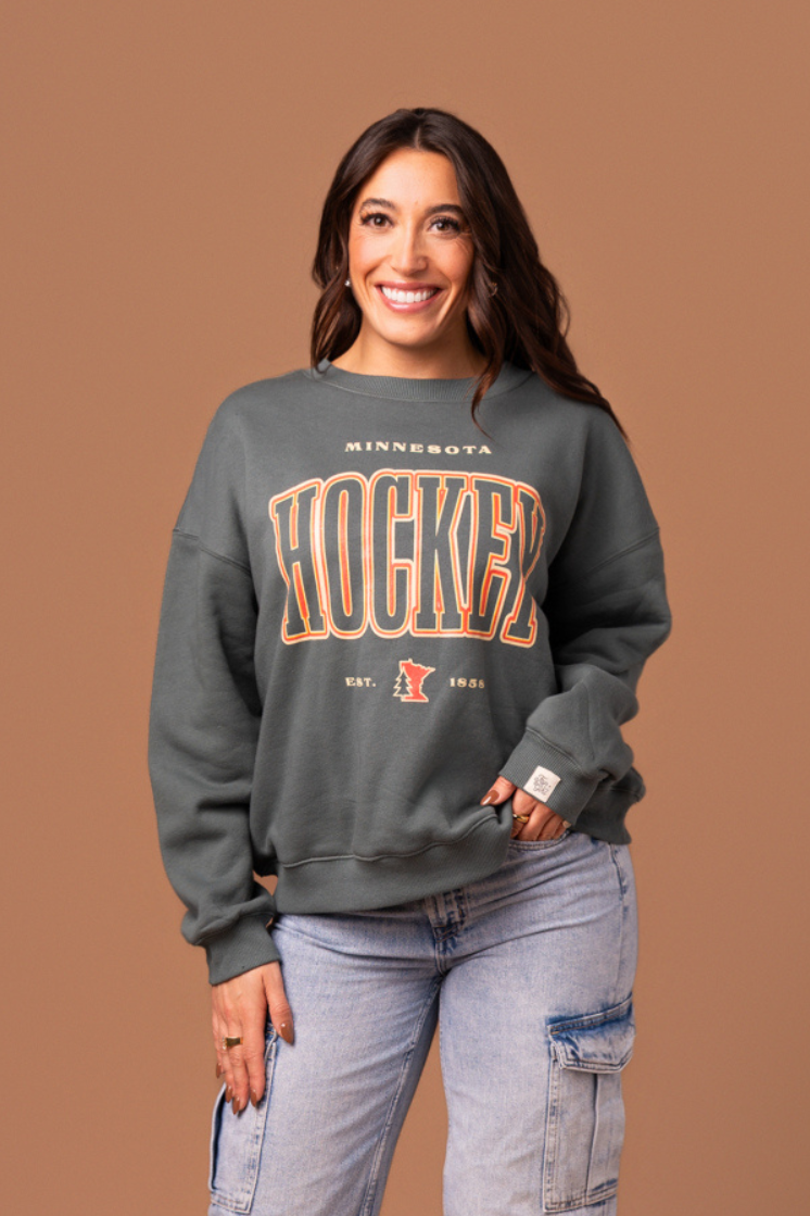 Woman wearing a green 'Minnesota Hockey' crew neck sweatshirt 