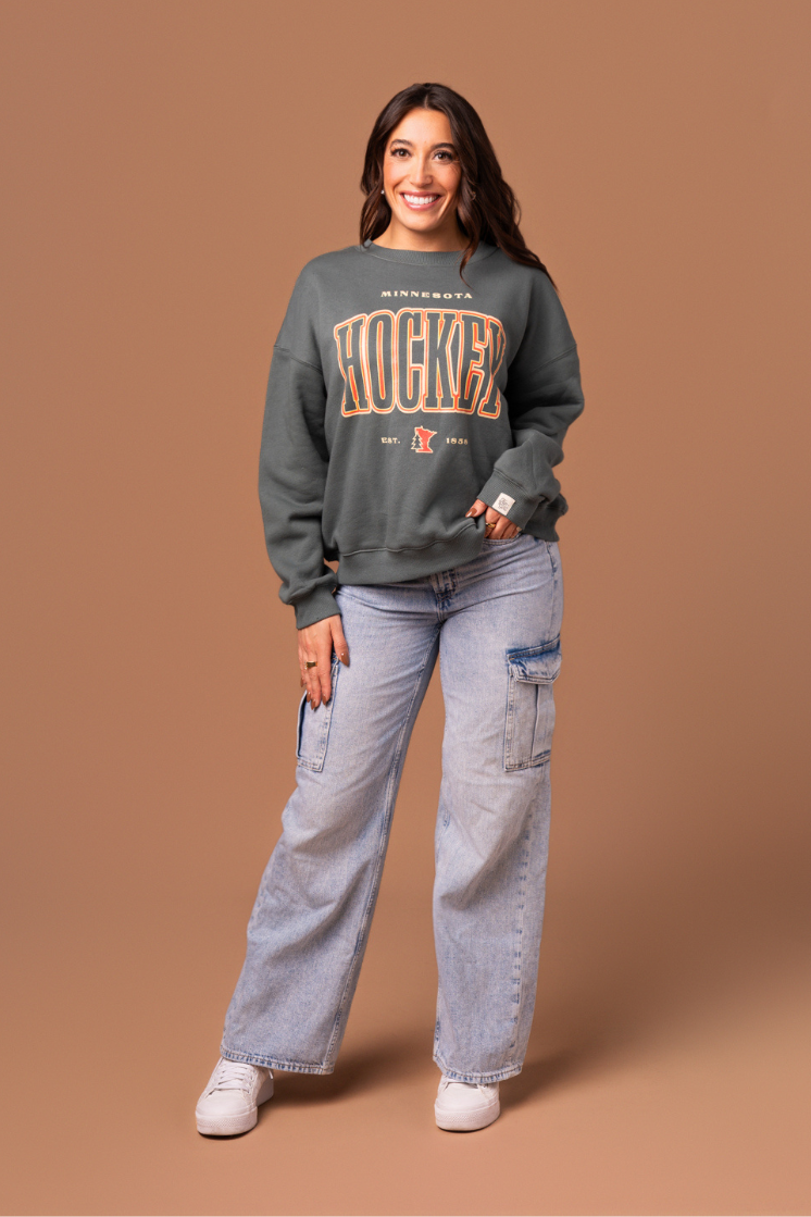 Woman wearing a green 'Minnesota Hockey' crew neck sweatshirt 