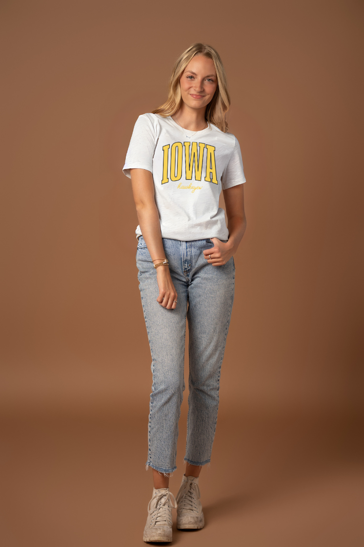 Woman wearing a white t-shirt with 'Iowa' printed on it against a brown background