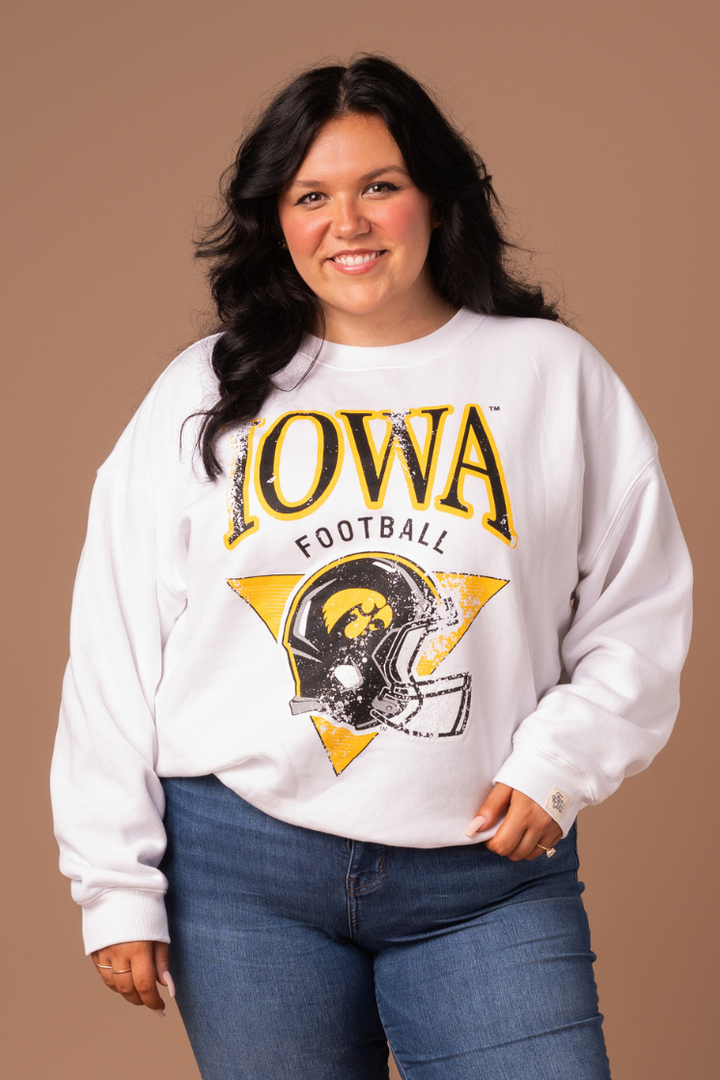 close up of a woman wearing a white crew neck sweatshirt with premium fleece lining that is made to fit women. The sweatshirt has black and yellow screenprinted Iowa Hawkeyes football design with a helmet and is distressed and vintage looking.