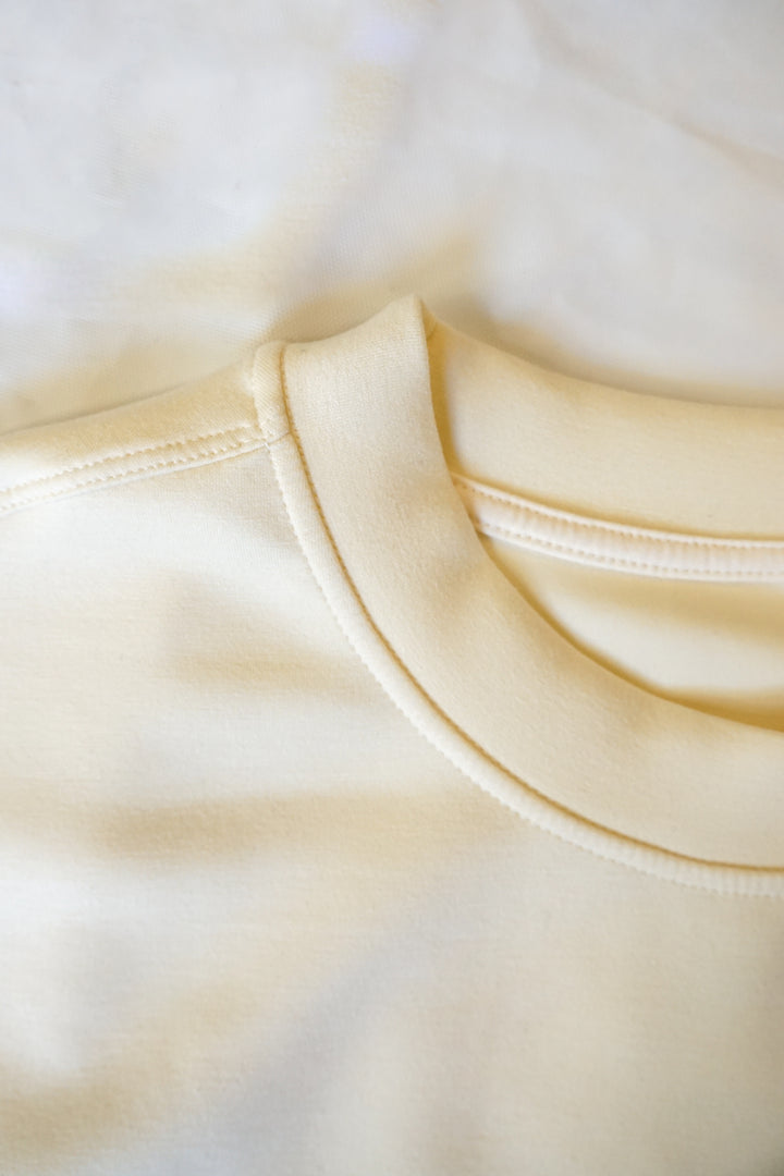 close up image of a collar of a cream colored supersoft crewneck 