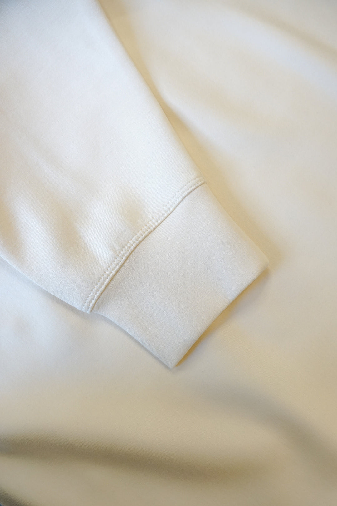 close up image of a sleeve of a cream colored supersoft crewneck 