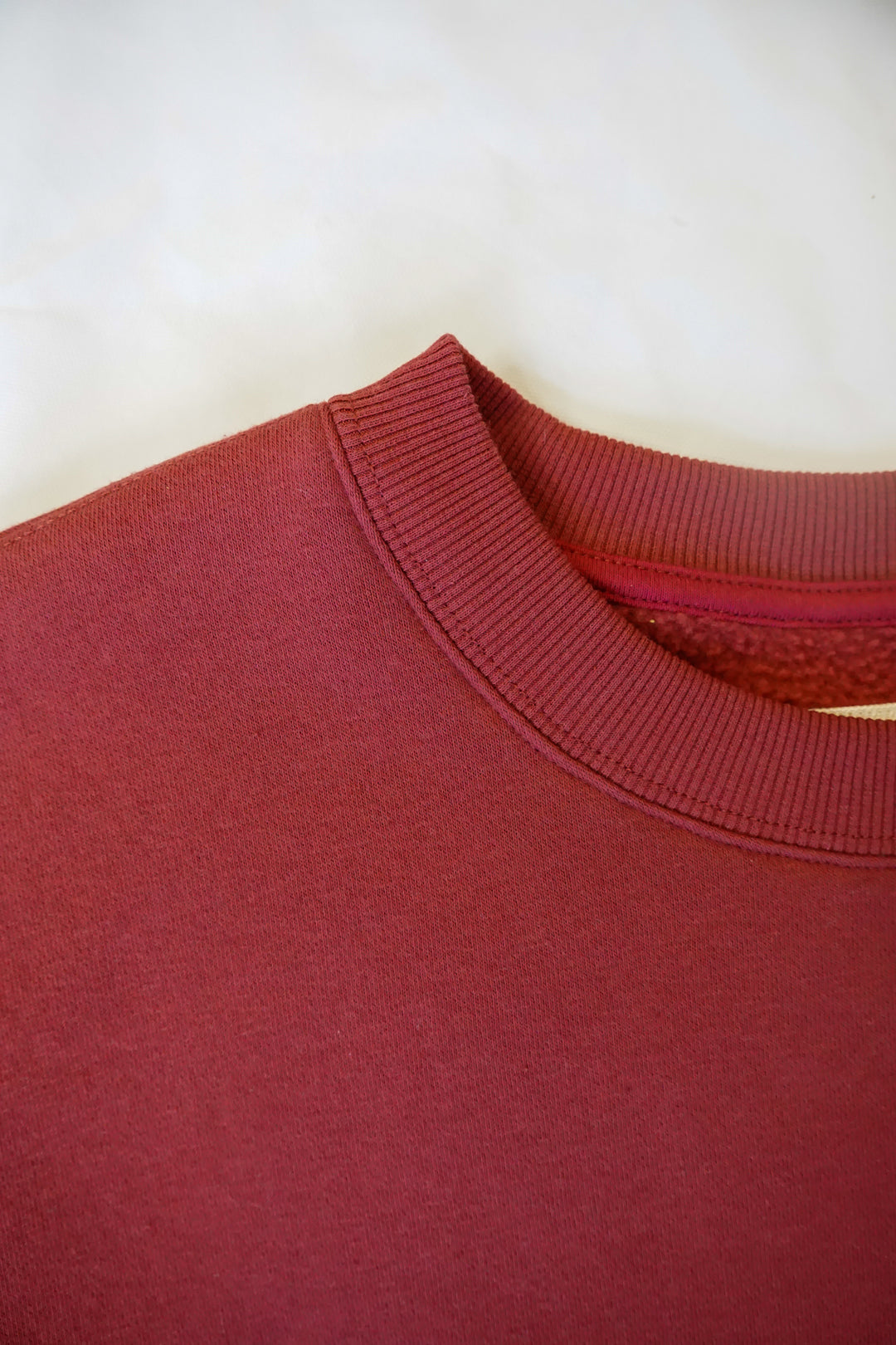 close up image of a collar of a maroon crewneck with a mock-neck like collar