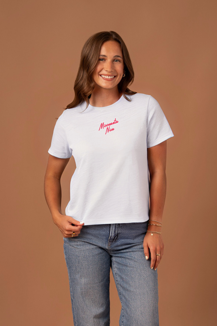 Woman wearing a white boxy cut t-shirt with red "Minnesota Nice" text 