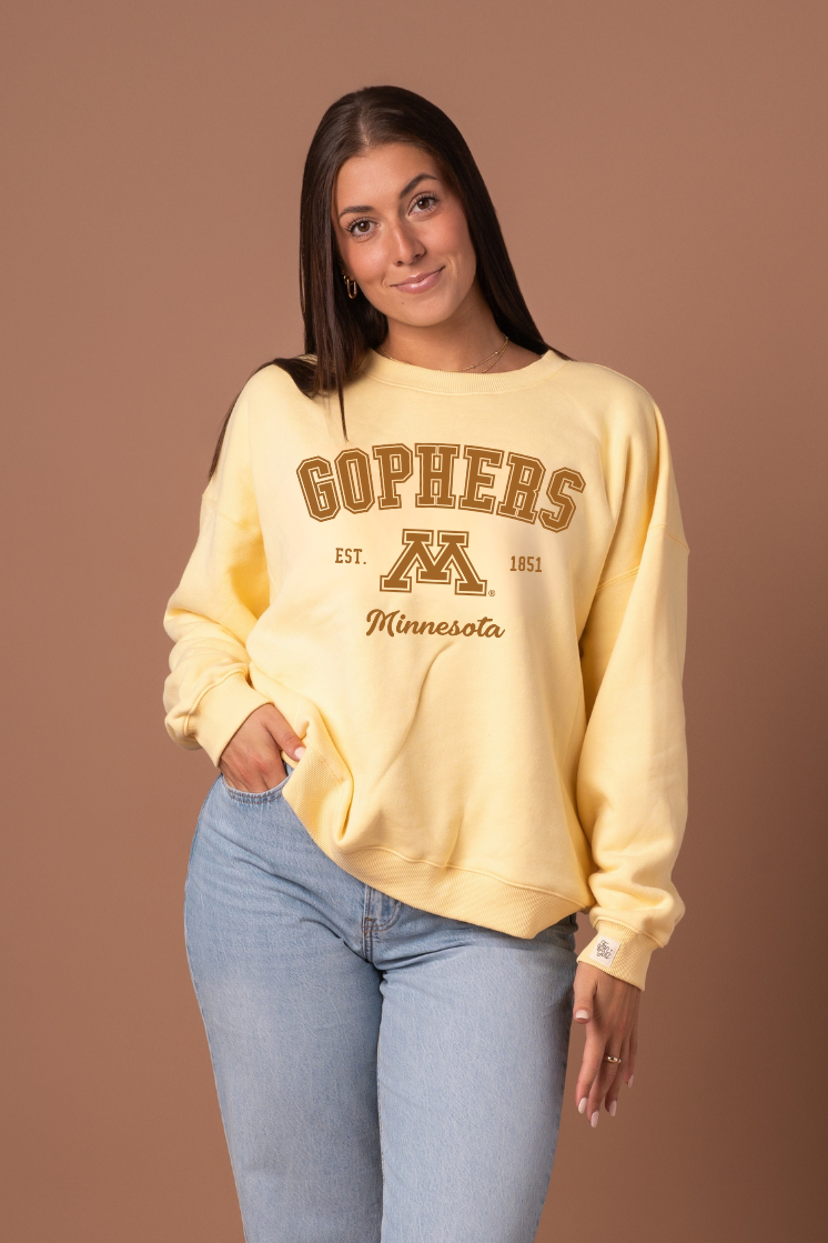 Woman wearing a yellow crew neck with 'Gophers' text and University of Minnesota logo under it