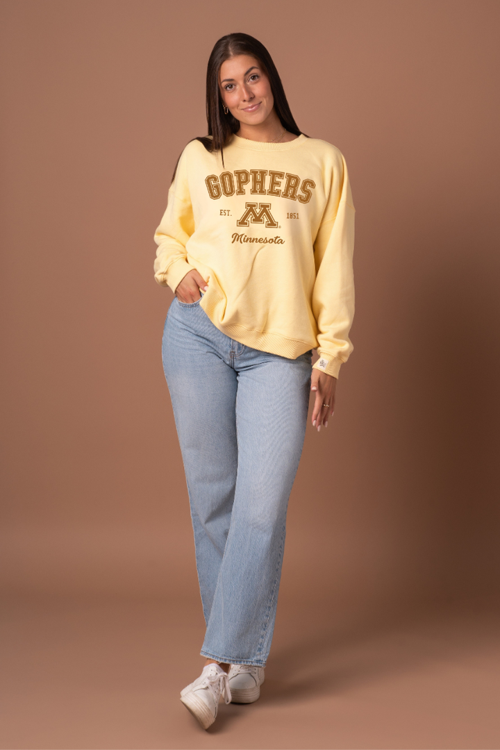 Woman wearing a yellow crew neck with 'Gophers' text and University of Minnesota logo under it