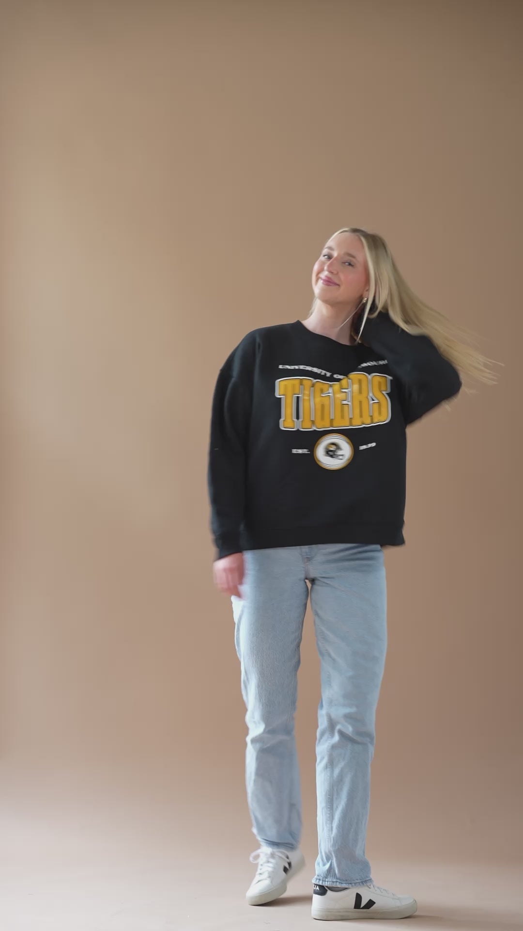 A video of a girl modeling a black crew neck with a University of Missouri Tigers design on the front in gold and white. 