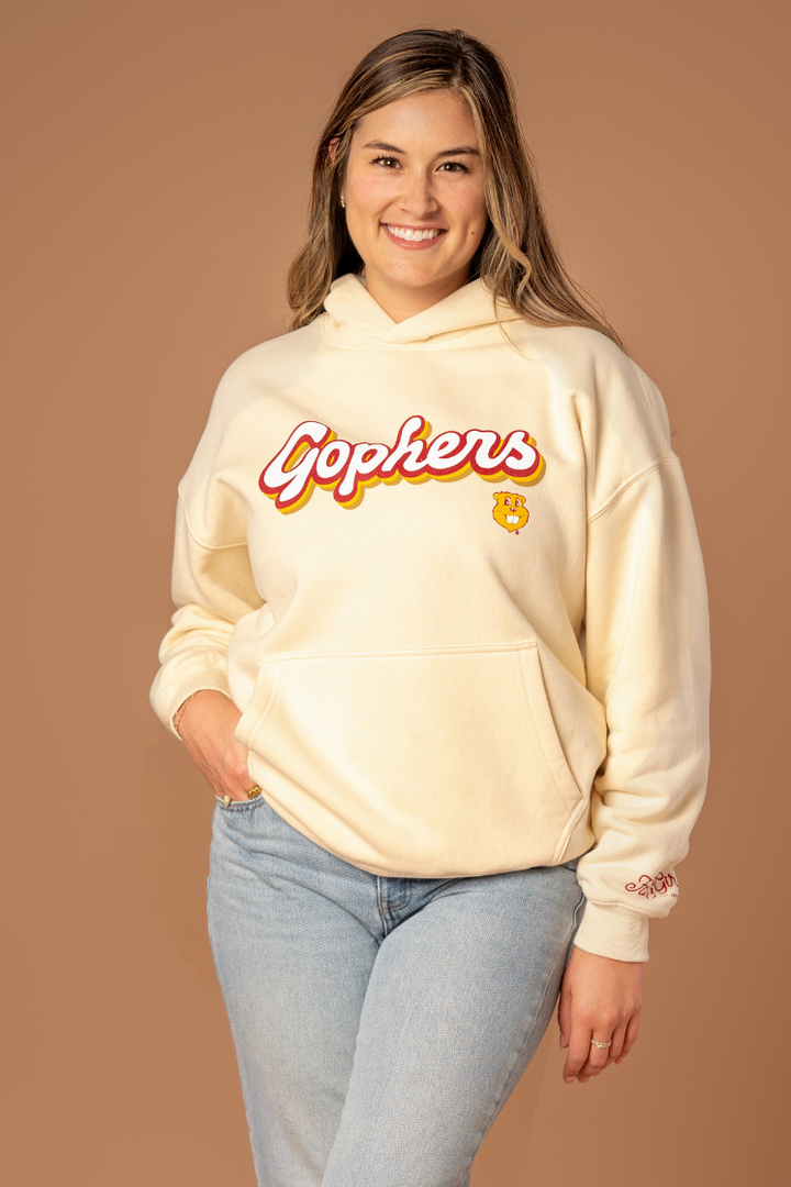 close up image of a girl wearing an ivory colored hoodie with a Gophers screenprint in a retro font with maroon and gold outlines with a Goldy head below it in gold