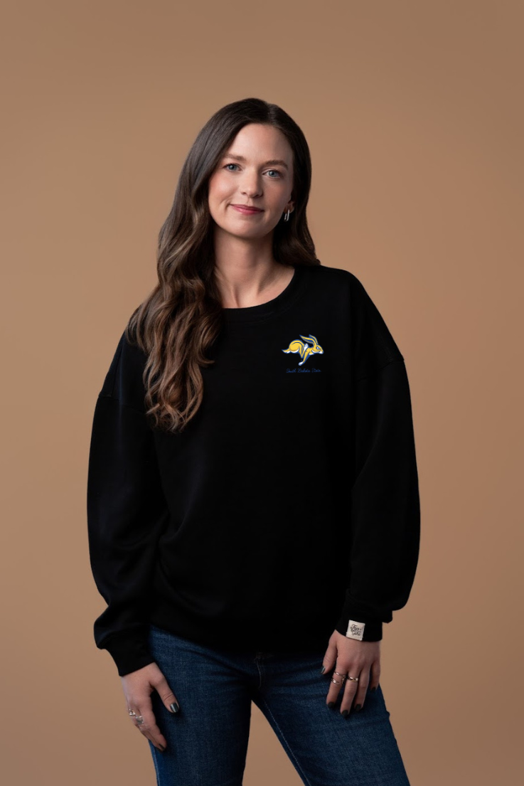 Woman wearing a black crew neck sweatshirt with a small Jackrabbit logo