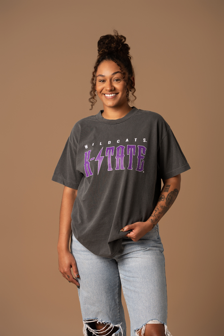 A woman wearing a vintage black T-shirt with 'K-STATE WILDCATS' and a lightning bolt graphic in purple and white.
