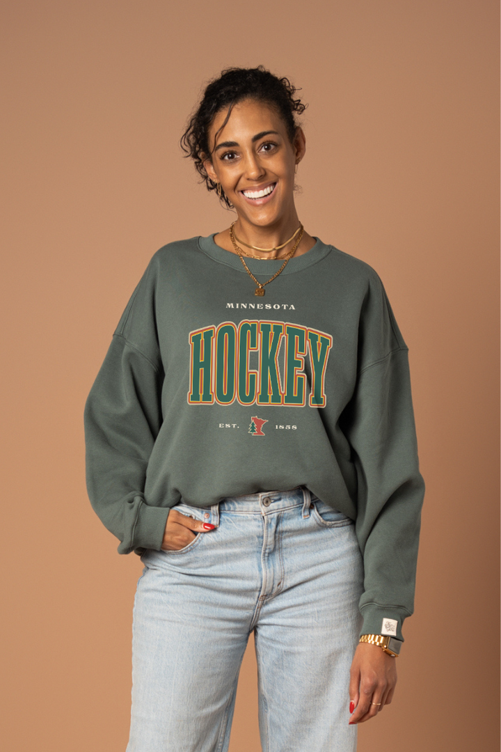 Woman wearing a green 'Minnesota Hockey' crew neck sweatshirt 