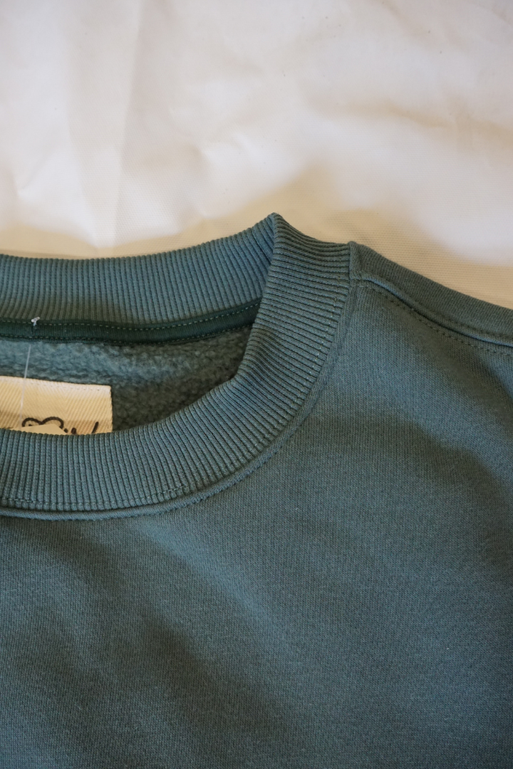 Close-up of a green crew neck sweatshirts neckline 