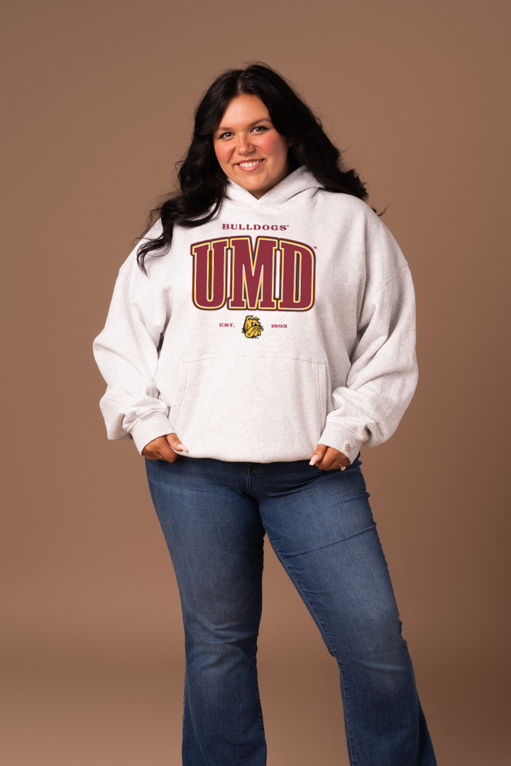 Girl wearing a grey hoodie with 'Bulldogs' and 'UMD' text in maroon with a yell/gold outline
