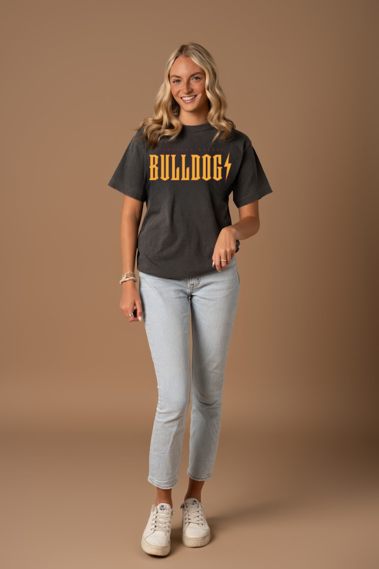 Picture of a woman wearing a ash grey t-shirt with 'Bulldogs' printed in yellow and maroon on a brown background