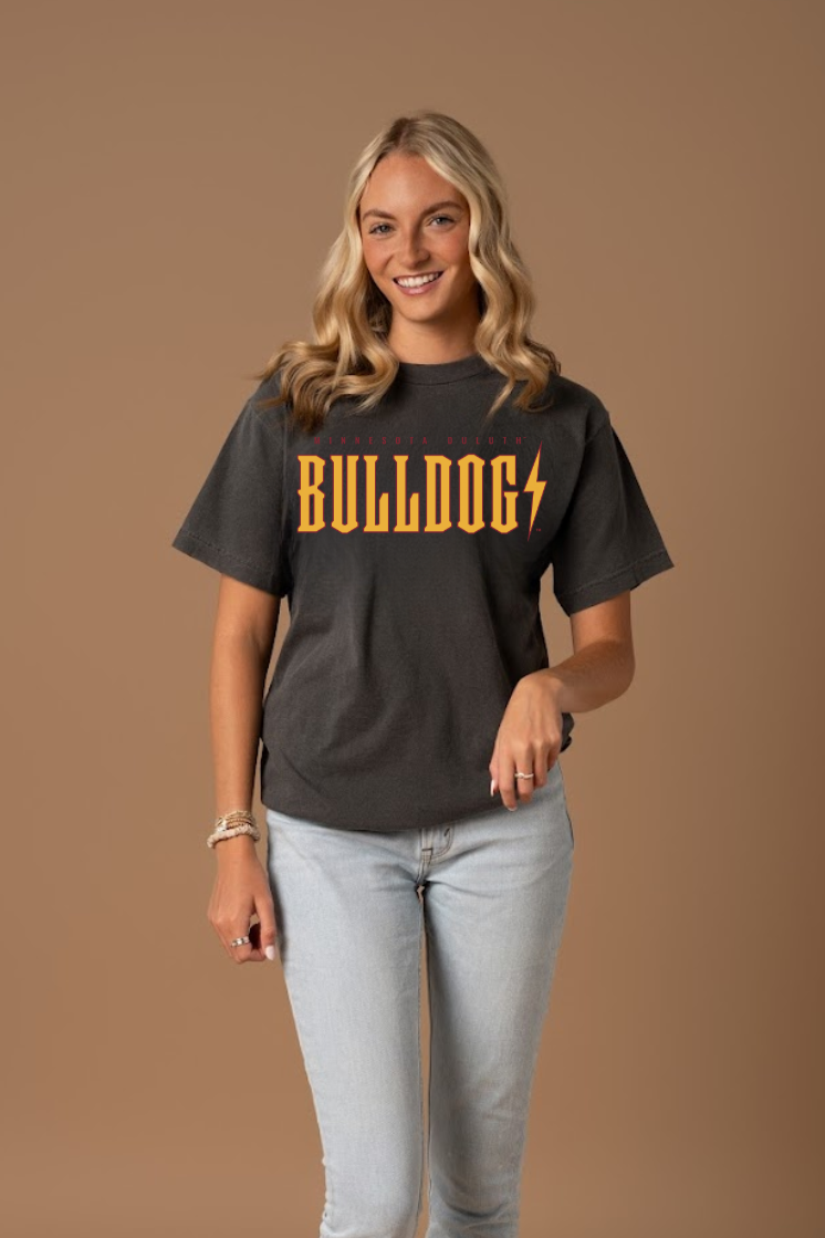 Close up picture of a woman wearing a ash grey t-shirt with 'Bulldogs' printed in yellow and maroon on a brown background