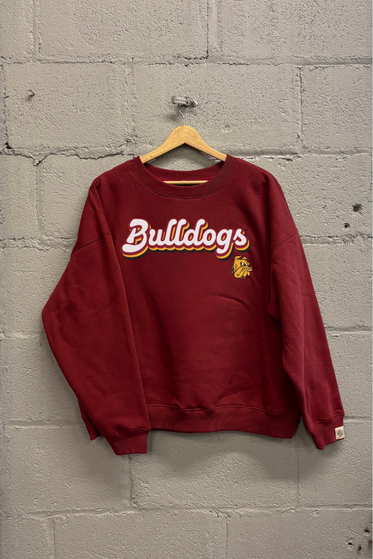 Maroon sweatshirt with 'Bulldogs' text on a wooden hanger against a gray brick wall.
