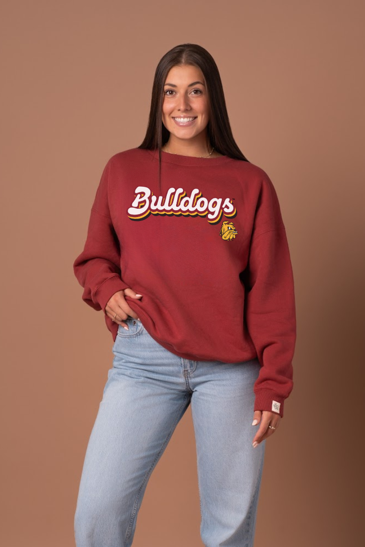 Girl wearing a maroon 'Bulldogs' sweatshirt against a brown background