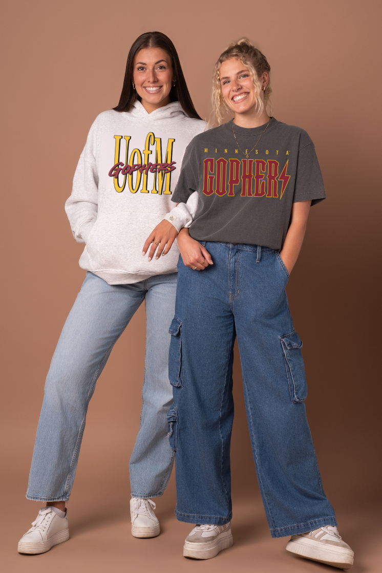 Two people wearing 'UofM' and 'Gophers' branded clothing on a brown background