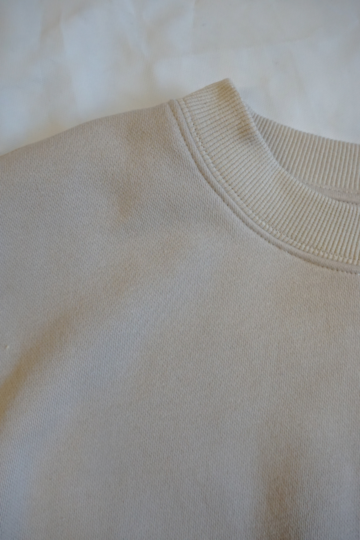 Collar of a beige crew neck sweatshirt