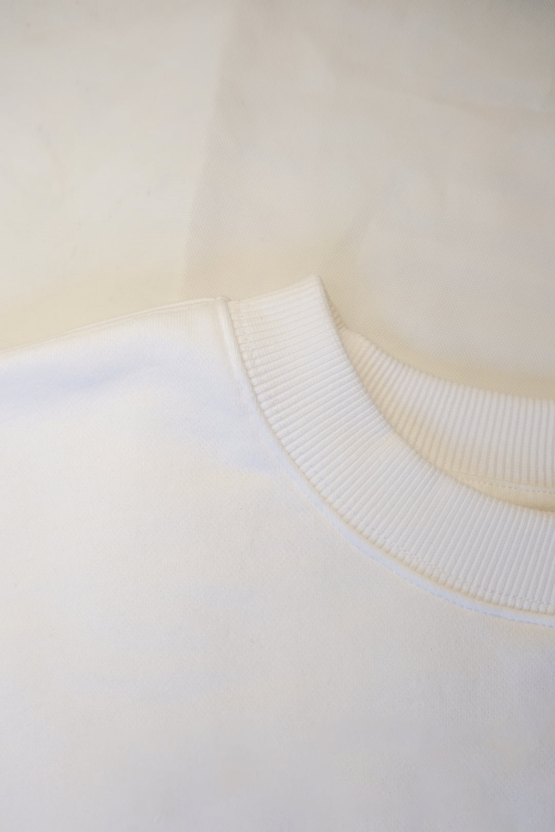 close up picture of a collar of a white fleece lined crew neck sweatshirt 