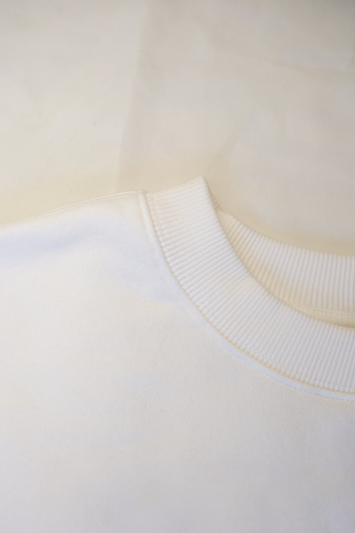 A close up photo of the thick mock-neck collar of a white crew neck.